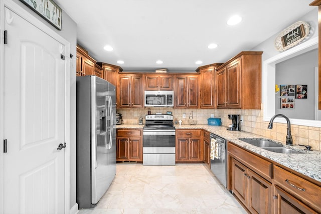 kitchen featuring sink, stainless steel appliances, light stone counters, and tasteful backsplash