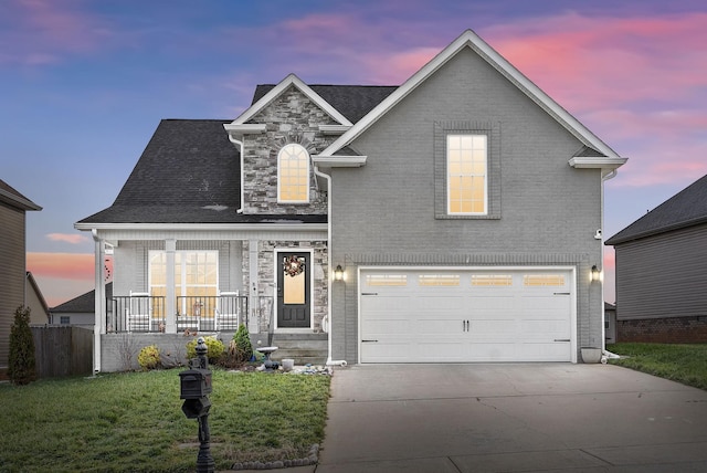 view of front of home with a garage, covered porch, and a yard