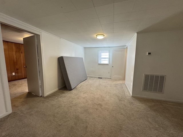 basement featuring crown molding, carpet floors, and wooden walls