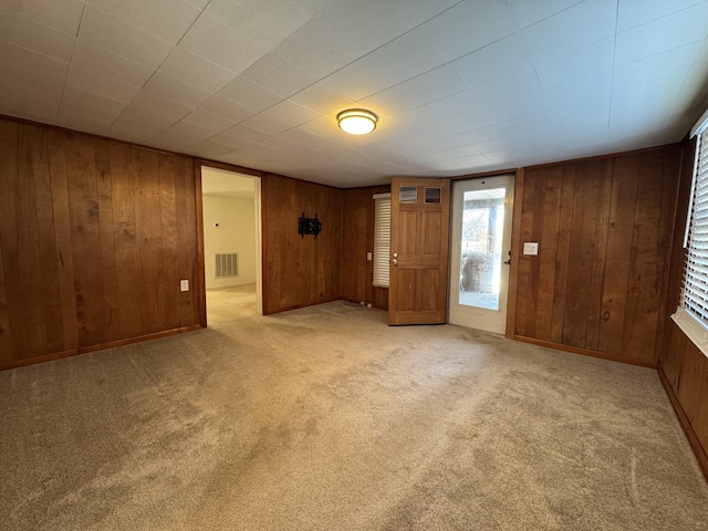 spare room featuring light carpet and wooden walls