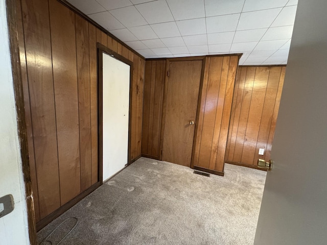 unfurnished bedroom with light carpet and wooden walls