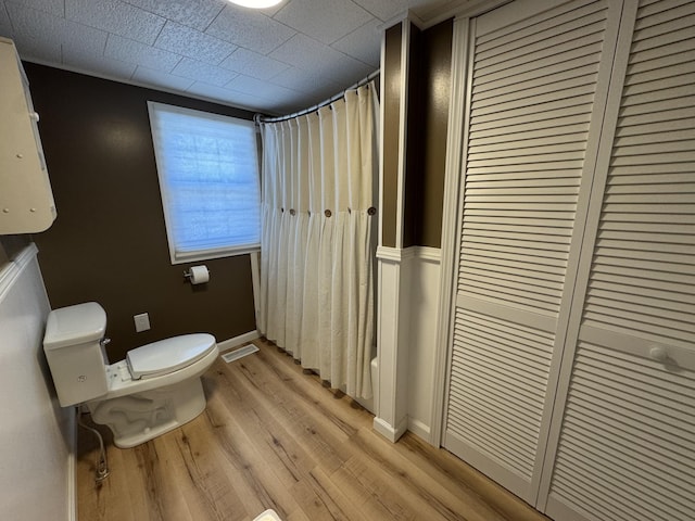 bathroom with wood-type flooring, shower / bath combo, and toilet