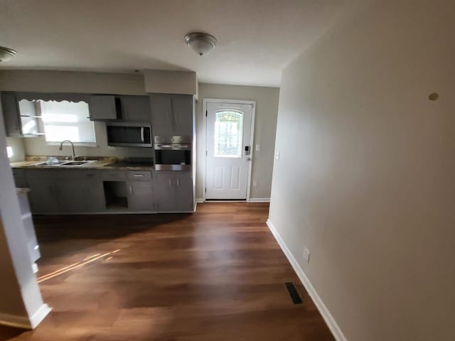 kitchen featuring dark hardwood / wood-style flooring, gray cabinets, sink, and stainless steel appliances