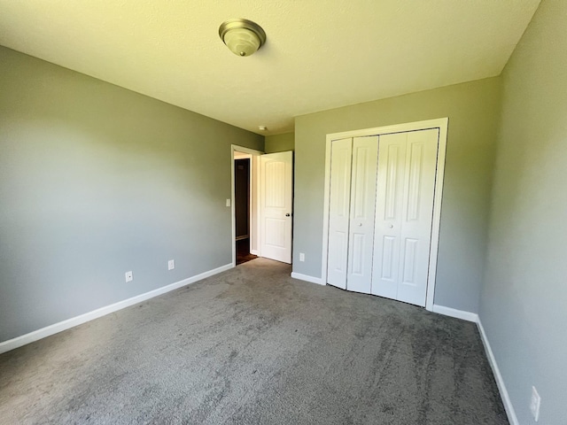 unfurnished bedroom featuring dark carpet and a closet