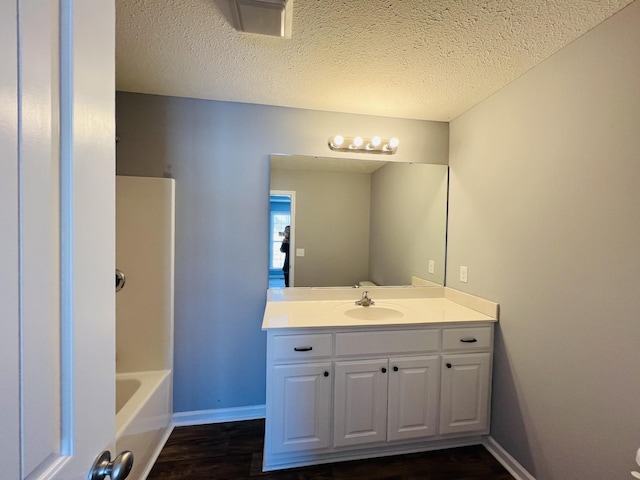 bathroom with vanity, hardwood / wood-style floors, a textured ceiling, and shower / washtub combination