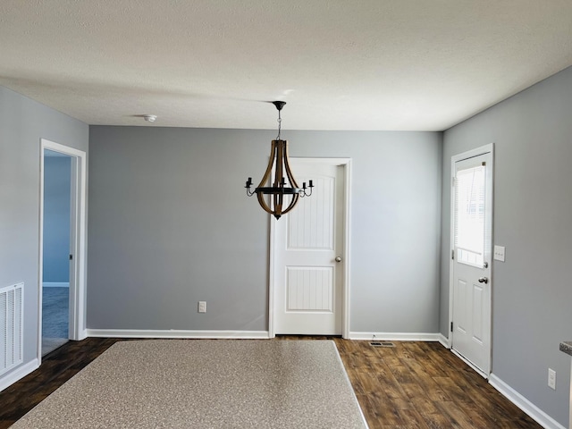 unfurnished dining area with dark wood-type flooring and a chandelier