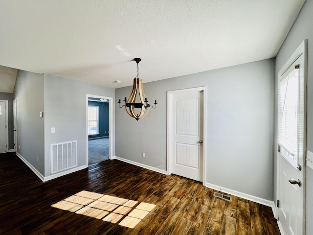 unfurnished dining area featuring dark hardwood / wood-style floors and an inviting chandelier