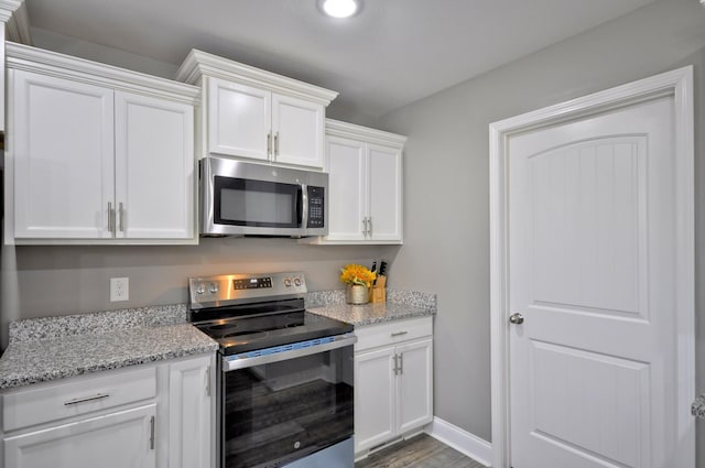 kitchen featuring light stone counters, hardwood / wood-style floors, stainless steel appliances, and white cabinets