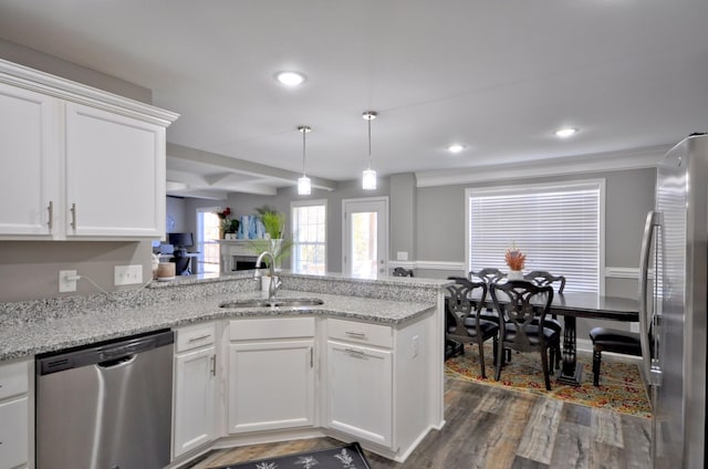 kitchen with stainless steel appliances, kitchen peninsula, sink, and white cabinets