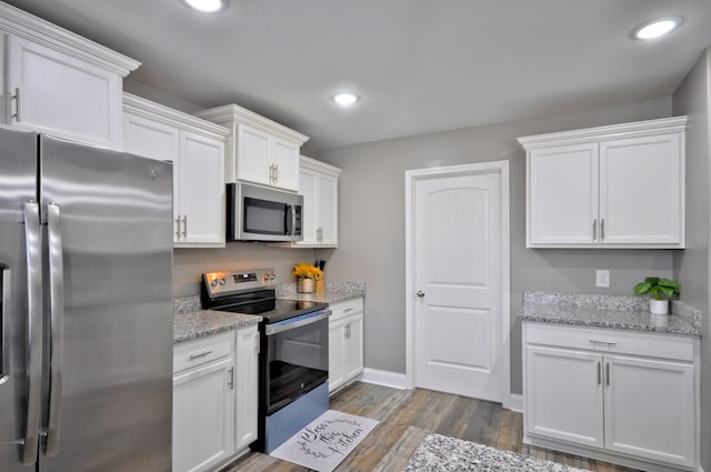 kitchen with light stone countertops, dark hardwood / wood-style floors, white cabinets, and appliances with stainless steel finishes