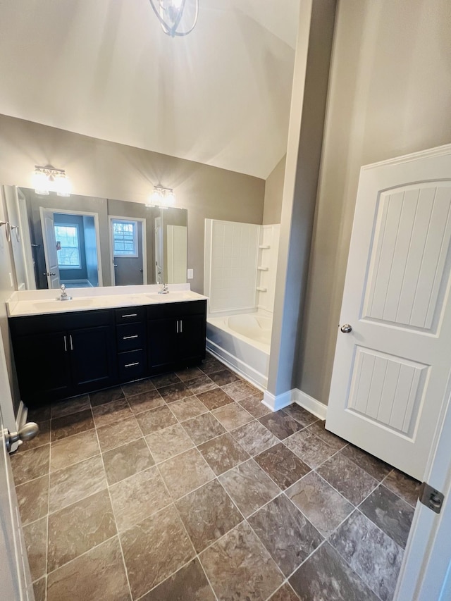 bathroom with lofted ceiling, vanity, and a bathtub