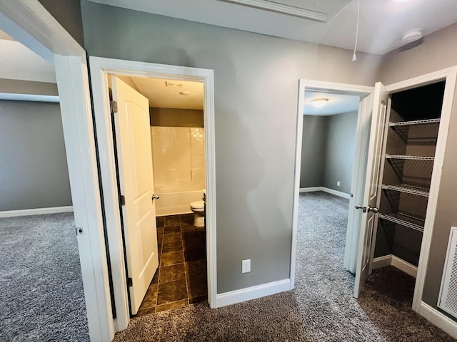 hallway featuring dark colored carpet