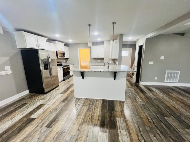 kitchen with appliances with stainless steel finishes, white cabinetry, hanging light fixtures, a kitchen breakfast bar, and light stone countertops