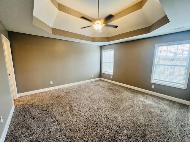 carpeted empty room featuring ceiling fan and a tray ceiling