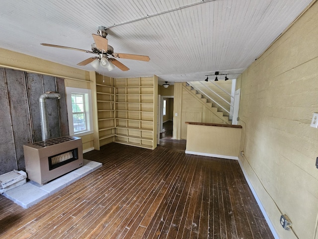 unfurnished living room with heating unit, ceiling fan, wooden walls, and hardwood / wood-style flooring