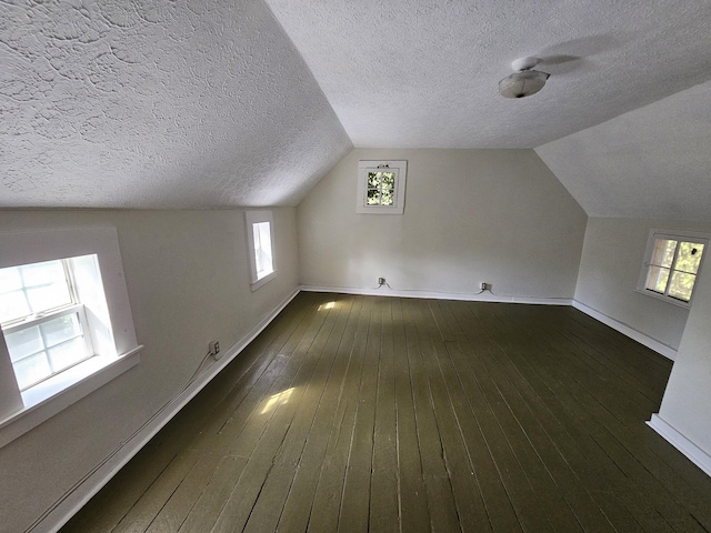 bonus room featuring a textured ceiling, a wealth of natural light, dark wood-type flooring, and lofted ceiling