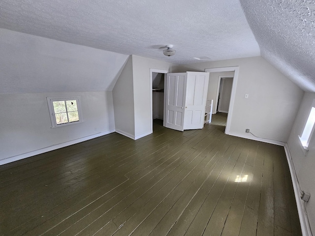 bonus room featuring a textured ceiling, dark hardwood / wood-style flooring, and lofted ceiling