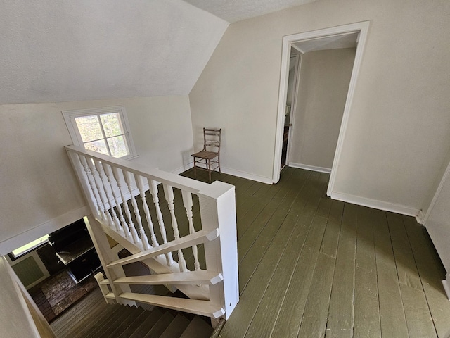 staircase featuring wood-type flooring, a textured ceiling, and lofted ceiling