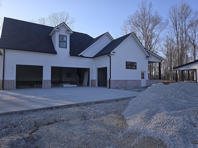 view of side of home with brick siding, roof with shingles, concrete driveway, and an attached garage