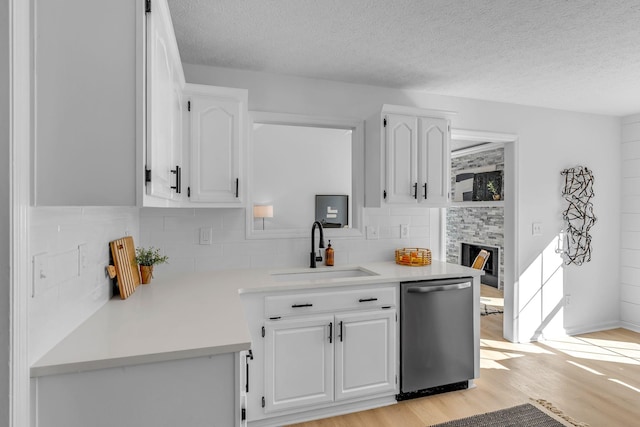 kitchen with light wood-type flooring, white cabinetry, stainless steel dishwasher, and sink