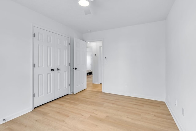 unfurnished bedroom with ceiling fan, a closet, and light wood-type flooring