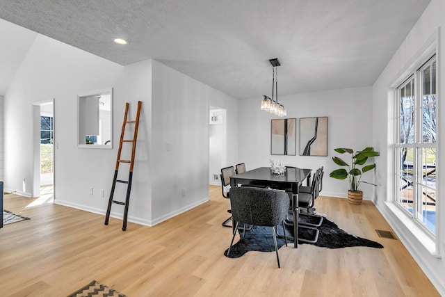 dining room featuring light wood-type flooring and a textured ceiling