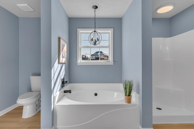 bathroom with a textured ceiling, hardwood / wood-style floors, an inviting chandelier, toilet, and plus walk in shower