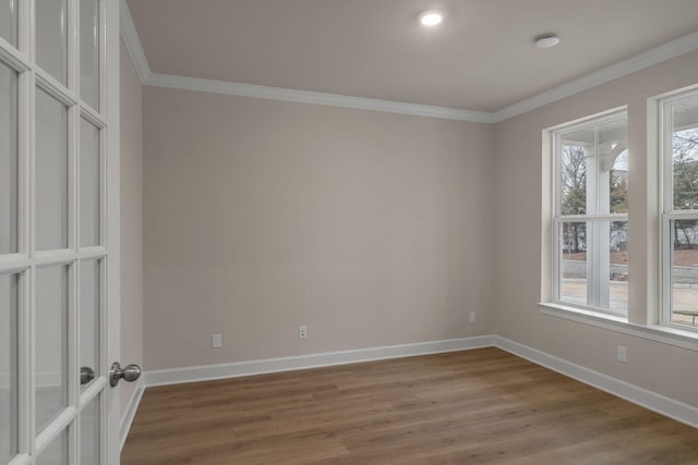 spare room featuring ornamental molding, wood-type flooring, and a wealth of natural light