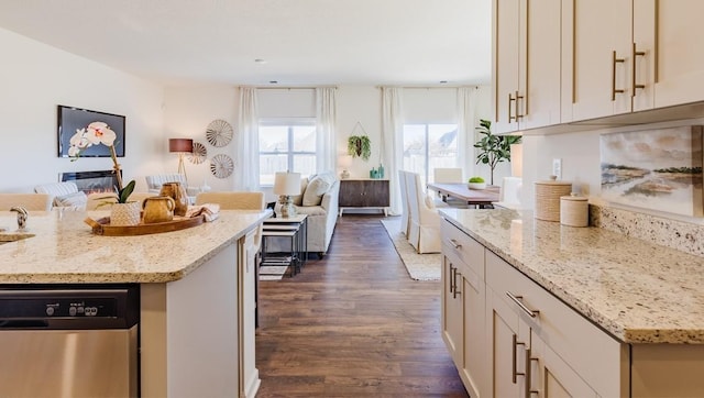 kitchen with light stone countertops, a kitchen island, stainless steel dishwasher, and dark wood-type flooring