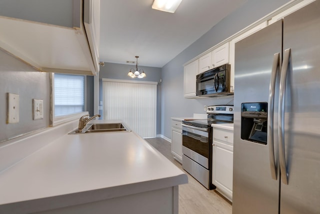 kitchen featuring stainless steel appliances, sink, decorative light fixtures, a notable chandelier, and white cabinetry