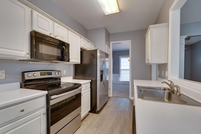 kitchen with sink, white cabinets, light hardwood / wood-style floors, and appliances with stainless steel finishes