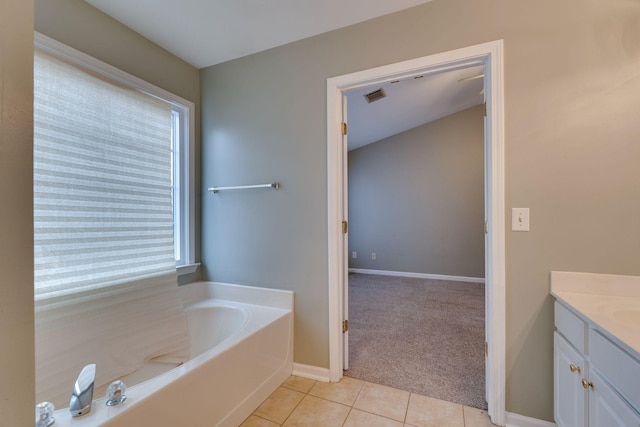 bathroom with a washtub, vanity, tile patterned floors, and plenty of natural light