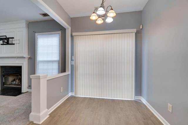 unfurnished dining area with a large fireplace and a chandelier