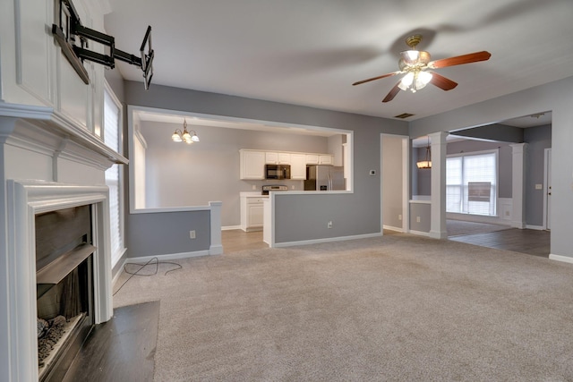 unfurnished living room with dark colored carpet and ceiling fan with notable chandelier