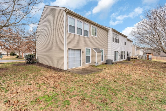 back of house with a lawn, a garage, central air condition unit, and a patio