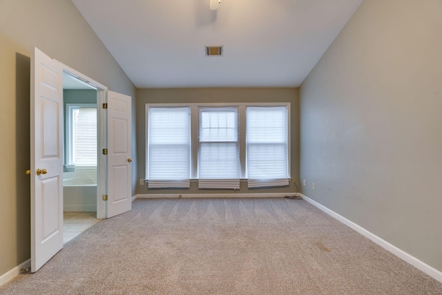 spare room featuring light carpet and vaulted ceiling