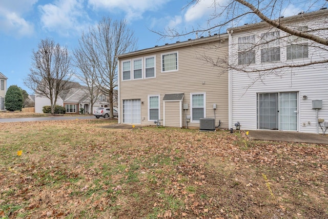 back of property with a yard, central AC, and a garage