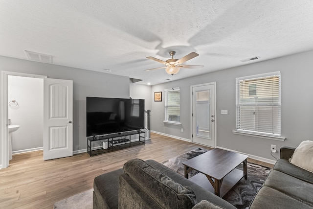 living room featuring ceiling fan, a wealth of natural light, and light hardwood / wood-style flooring