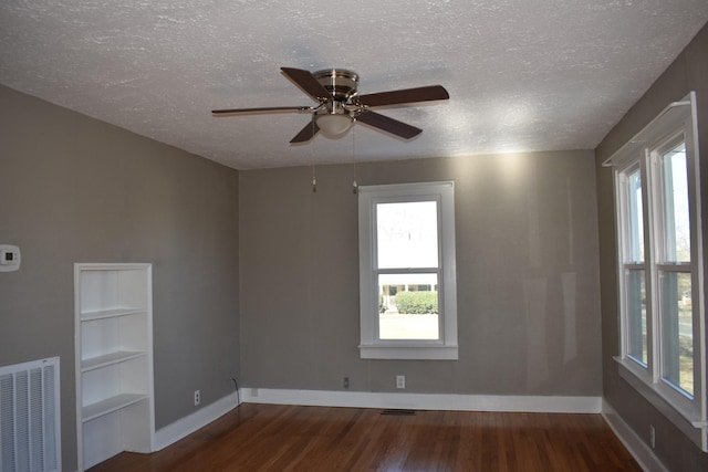 empty room with ceiling fan, dark wood-type flooring, and a textured ceiling