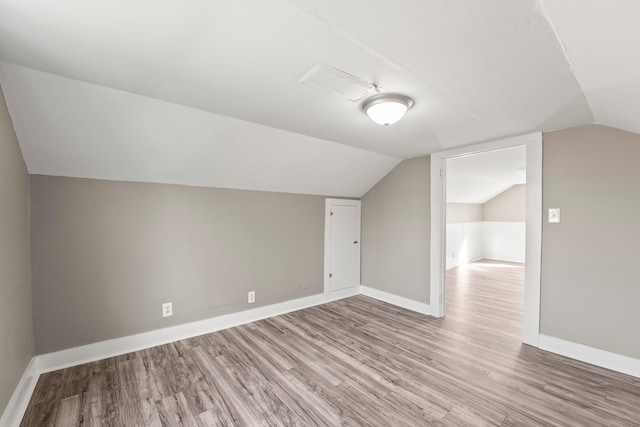 additional living space featuring lofted ceiling and light wood-type flooring