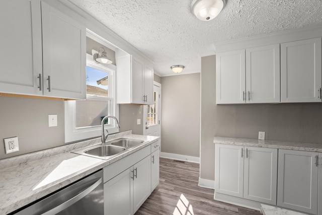 kitchen featuring light stone counters, white cabinets, stainless steel dishwasher, and sink