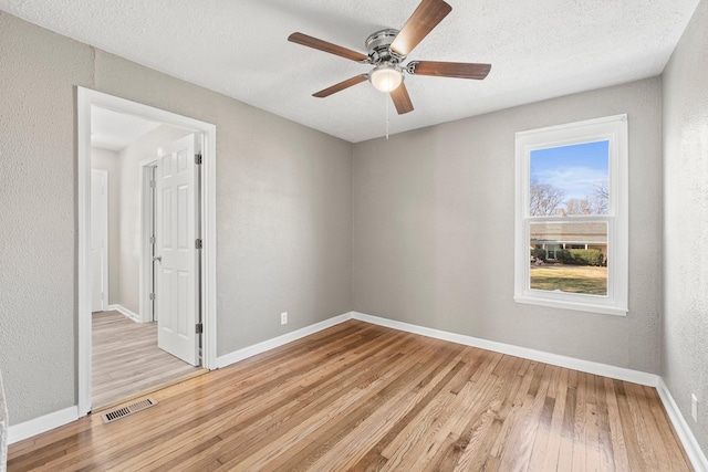 empty room featuring ceiling fan, a textured ceiling, and light wood-type flooring