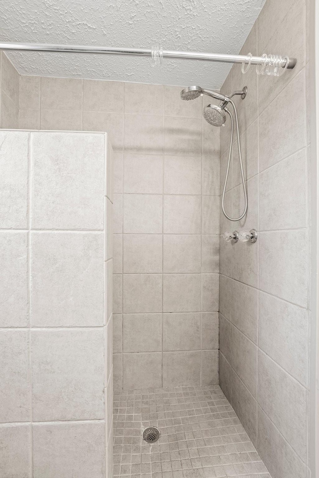 bathroom featuring a textured ceiling and tiled shower