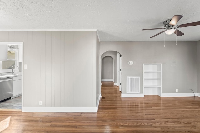 spare room with ceiling fan, wood-type flooring, sink, a textured ceiling, and built in shelves