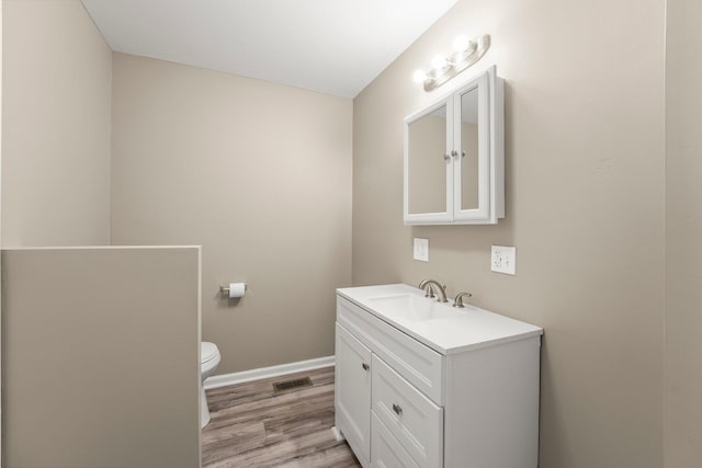 bathroom featuring toilet, vanity, and hardwood / wood-style floors