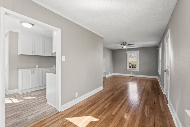 unfurnished living room with ceiling fan, a textured ceiling, and light hardwood / wood-style floors