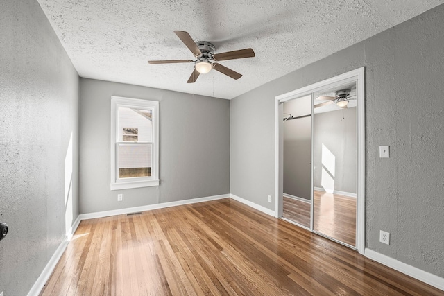 unfurnished bedroom featuring a textured ceiling, a closet, wood-type flooring, and ceiling fan