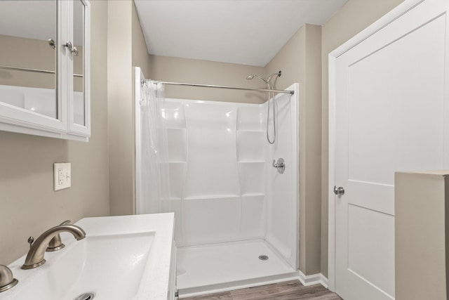 bathroom with walk in shower, sink, and hardwood / wood-style floors