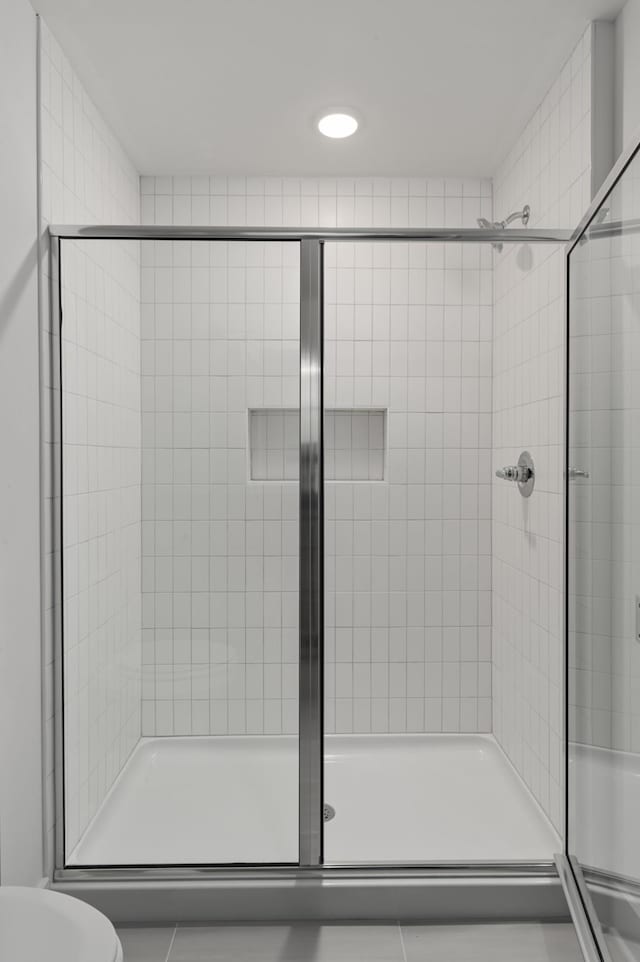 bathroom featuring a shower with door and toilet