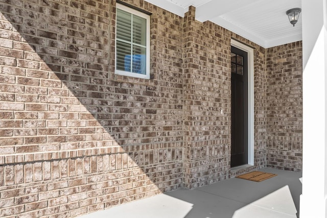 entrance to property with covered porch and brick siding